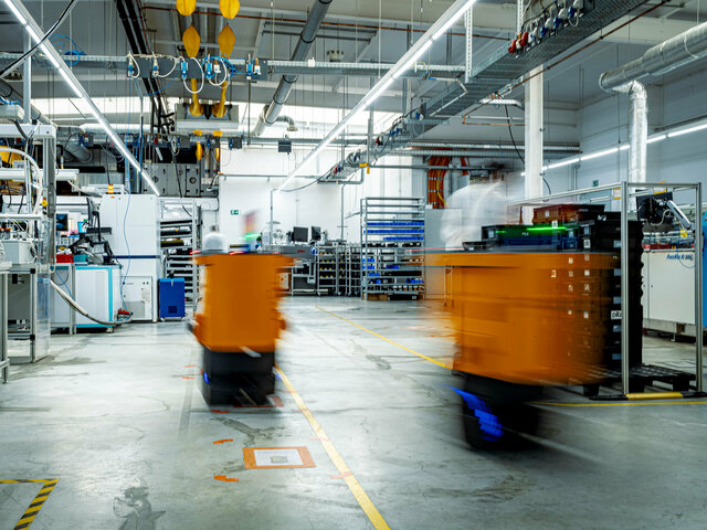 Two AGVs transport RevPi devices to the THT wave soldering system in production